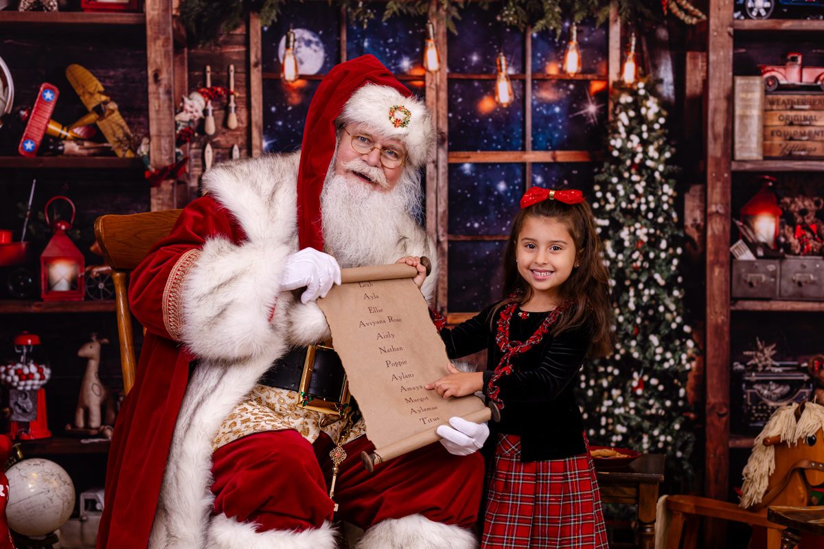 girl pointing to nice list with santa during a photo session in palm harbor