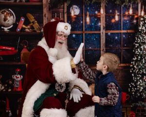 young boy gives santa claus a high five during his photo sessions 